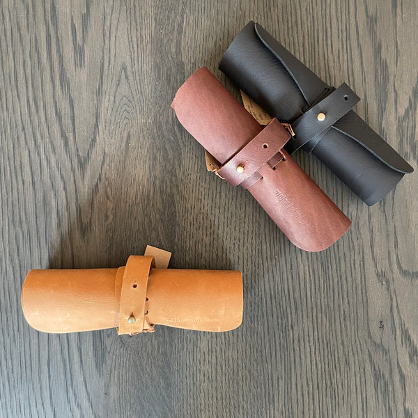 A variety of tan , chocolate and black cable and pen roll-ups , made from 100% leather
